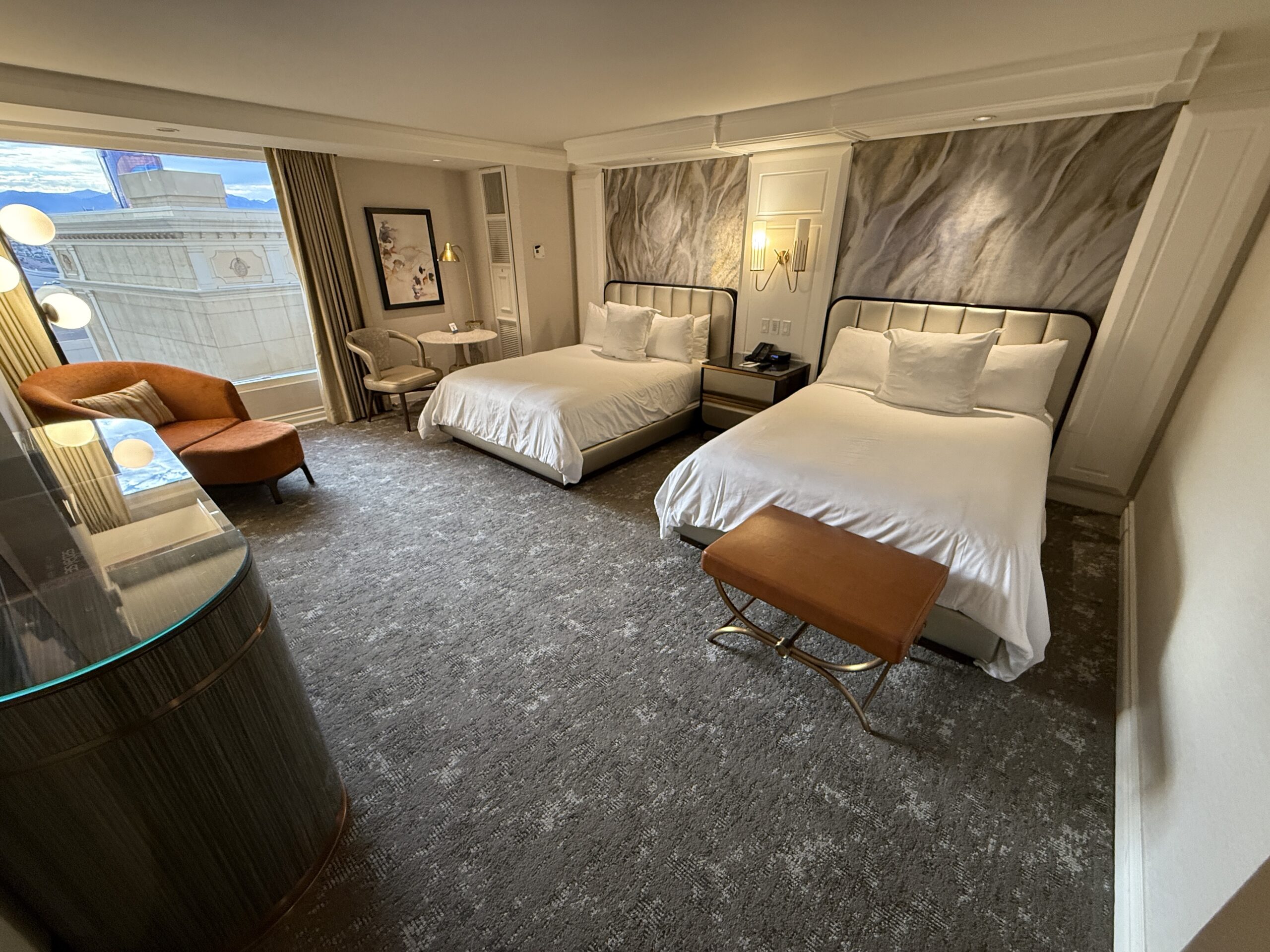A wide angle shot of the two queen beds on the back wall, with a window on the left.