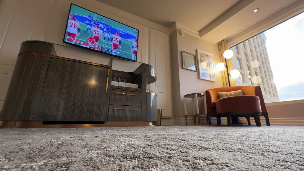 A view of the TV, TV Stand, and chair in front of the window shot from the floor. 
