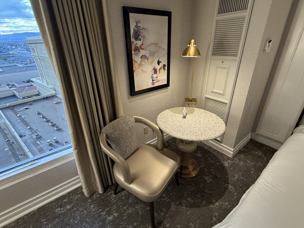 A small circular table with a chair next to it unnder an overhead light fixture.