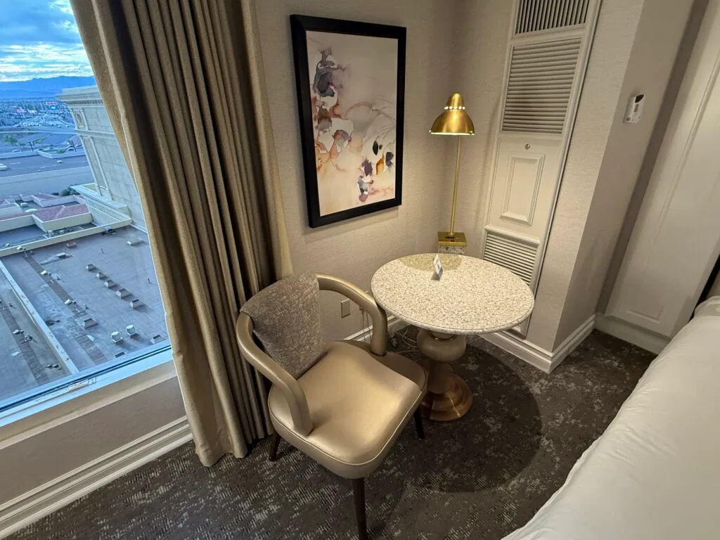 A small circular table with a chair next to it unnder an overhead light fixture. 