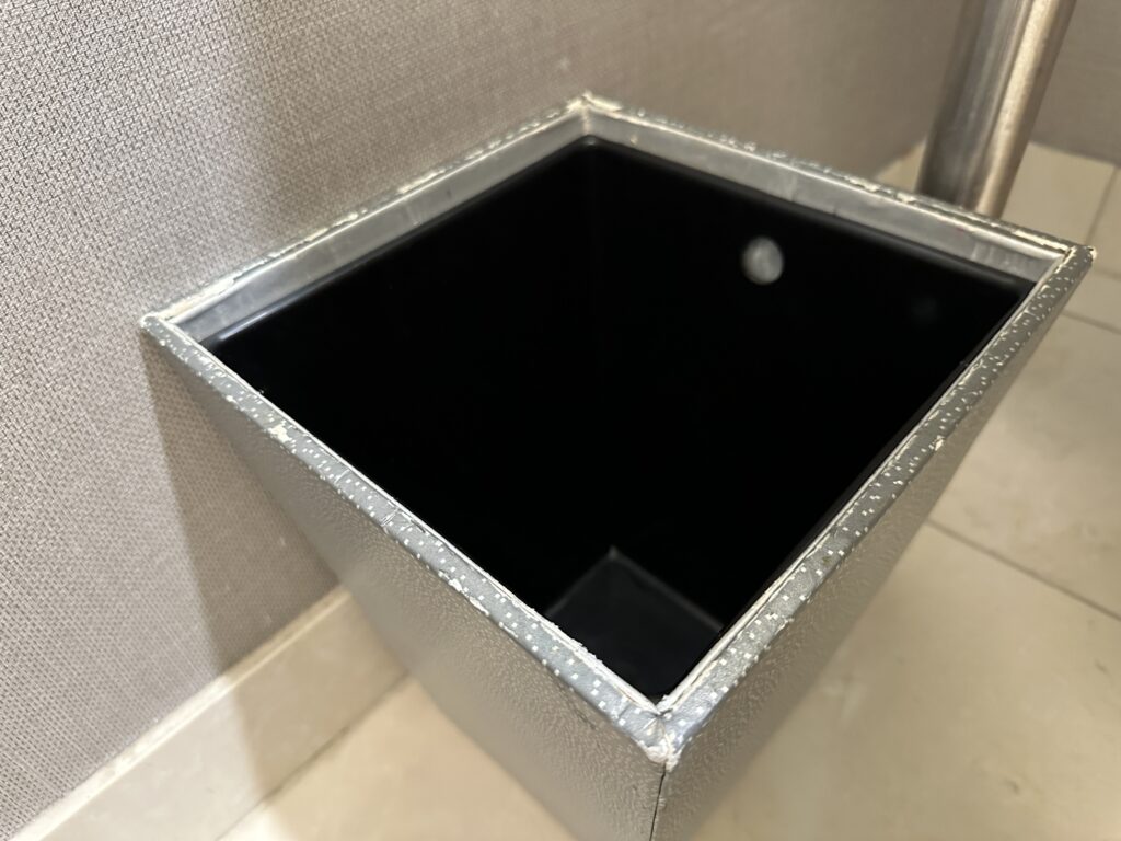 A small garbage can, with chips missing from the rim.