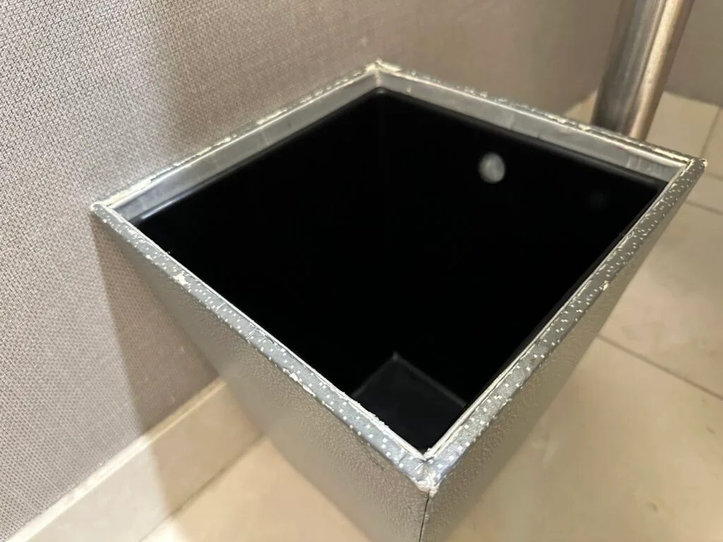 A small garbage can, with chips missing from the rim. 