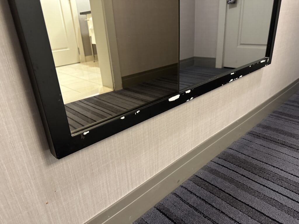 The entryway mirror, with chips missing from the frame.