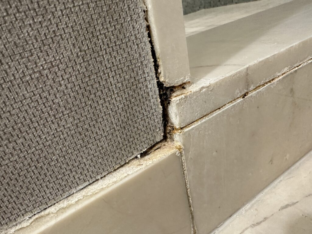 A discolored grout line on the exterior of the shower.