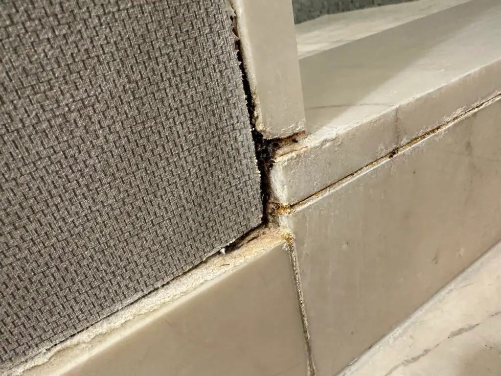 A discolored grout line on the exterior of the shower. 
