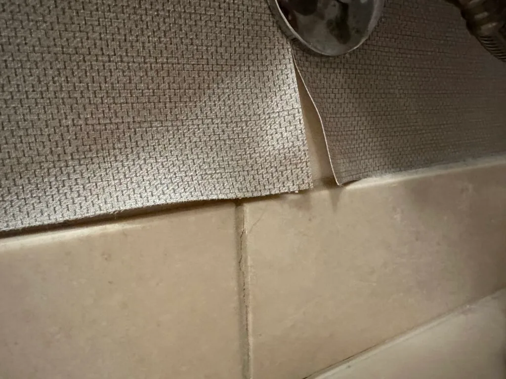 Peeling wallpaper behind the toilet. 