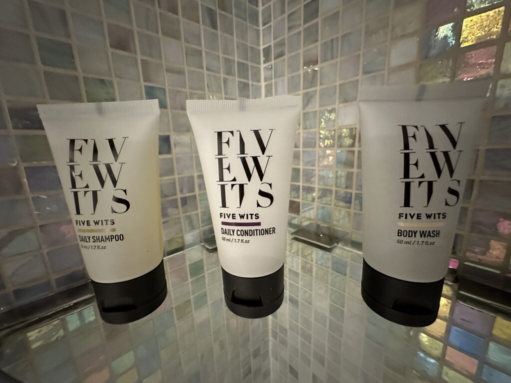 A row of 3 tubes of toiletries. on a shelf in the shower.