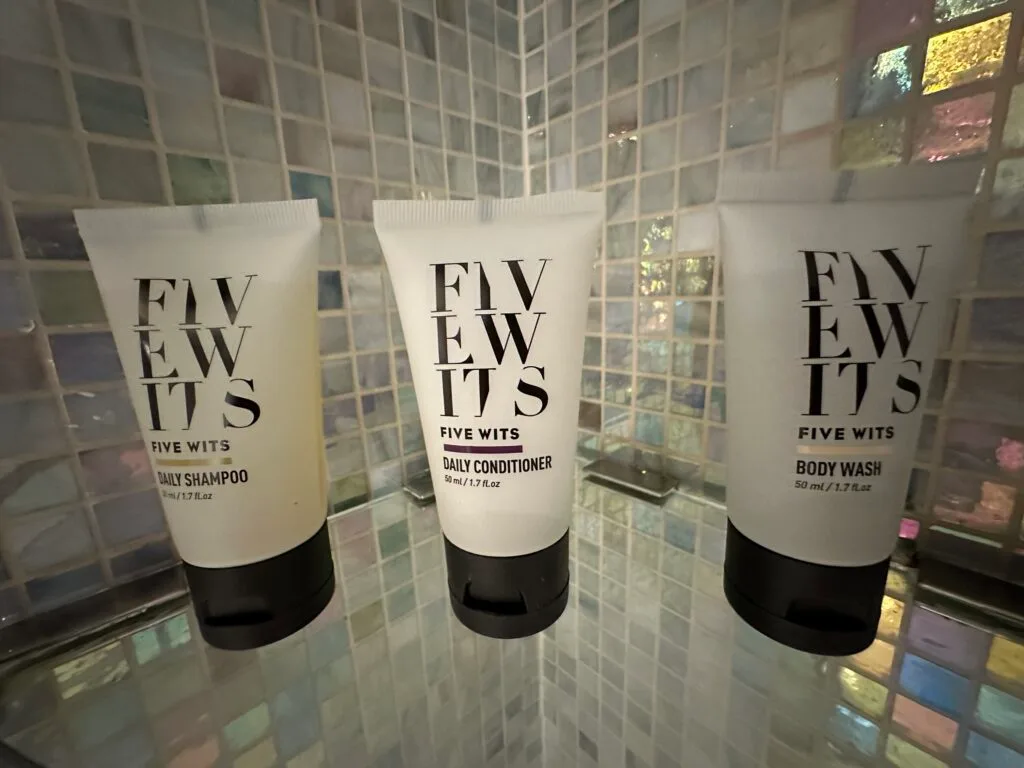 A row of 3 tubes of toiletries. on a shelf in the shower. 