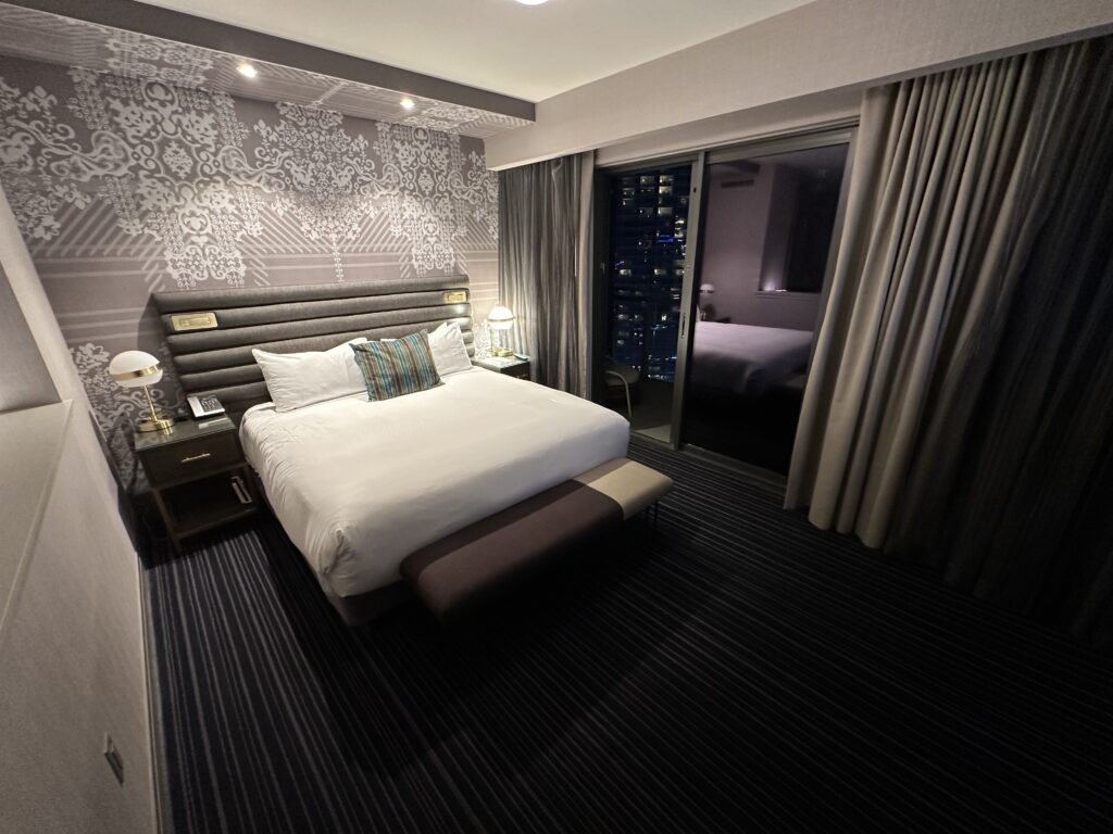 The king bed, illuminated from above, with the sliding glass door the balcony on the right.