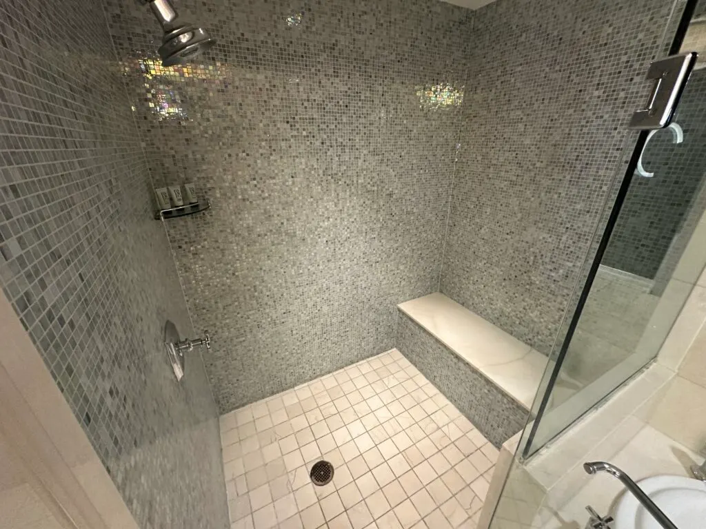 A look inside the shower, which has black tile walls,and a bench. 