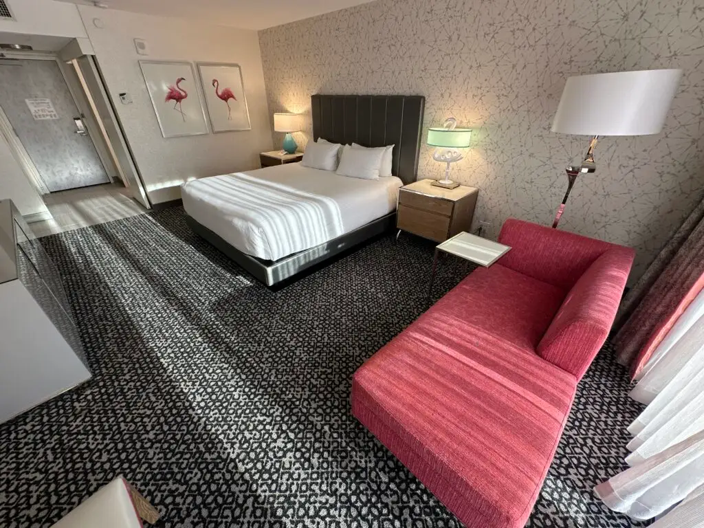 Another angle, from the window, that shows a pink couch in the foreground with the bed in the background. 