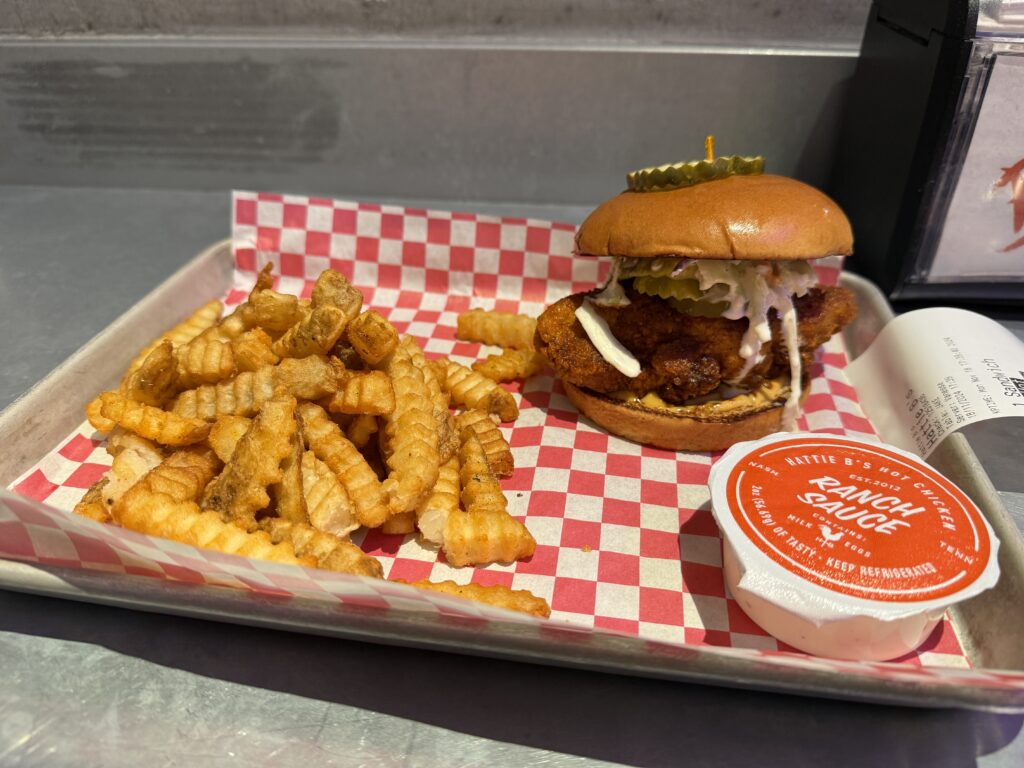 A chicken sandwich on a tray next to a pile of french fries.