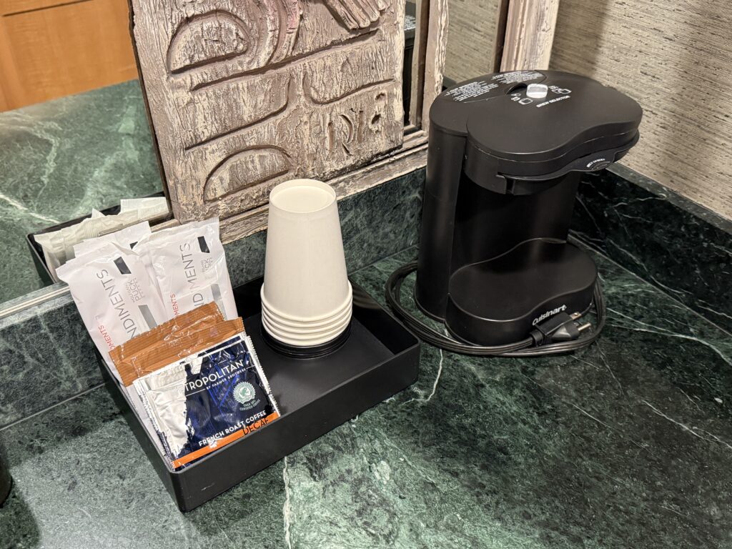 A coffee machine next to free coffee and cups.