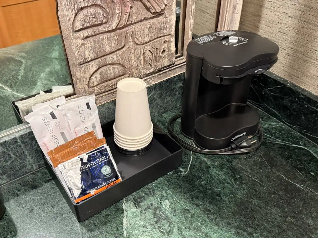 A coffee machine next to free coffee and cups. 