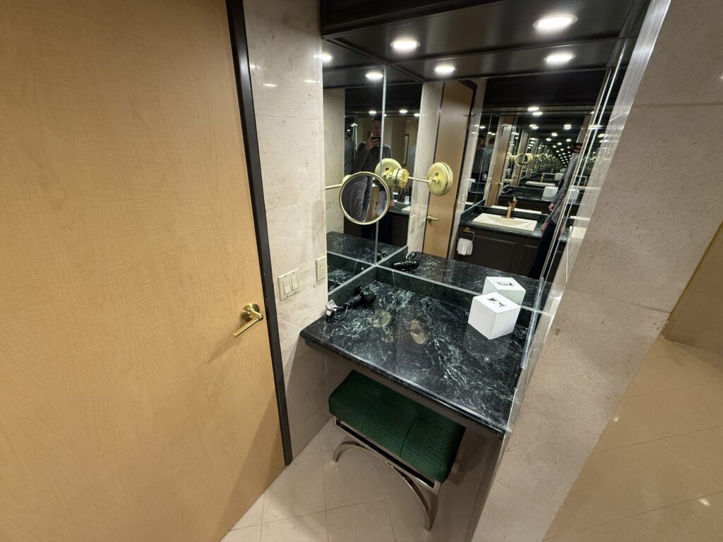A separate powder station with a pull out stool, green countertops, and plenty of mirrors.