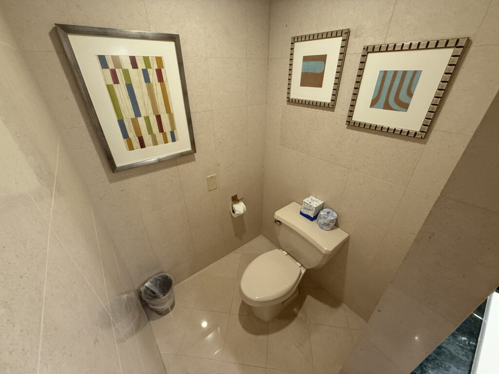 A toilet in the corner with 3 pictures hanging around it.
