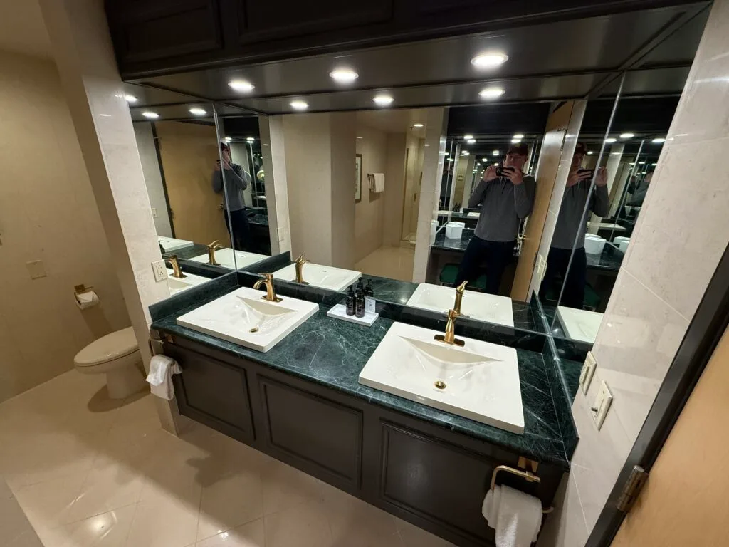 A dual vanity sink, with emerald green countertops. 