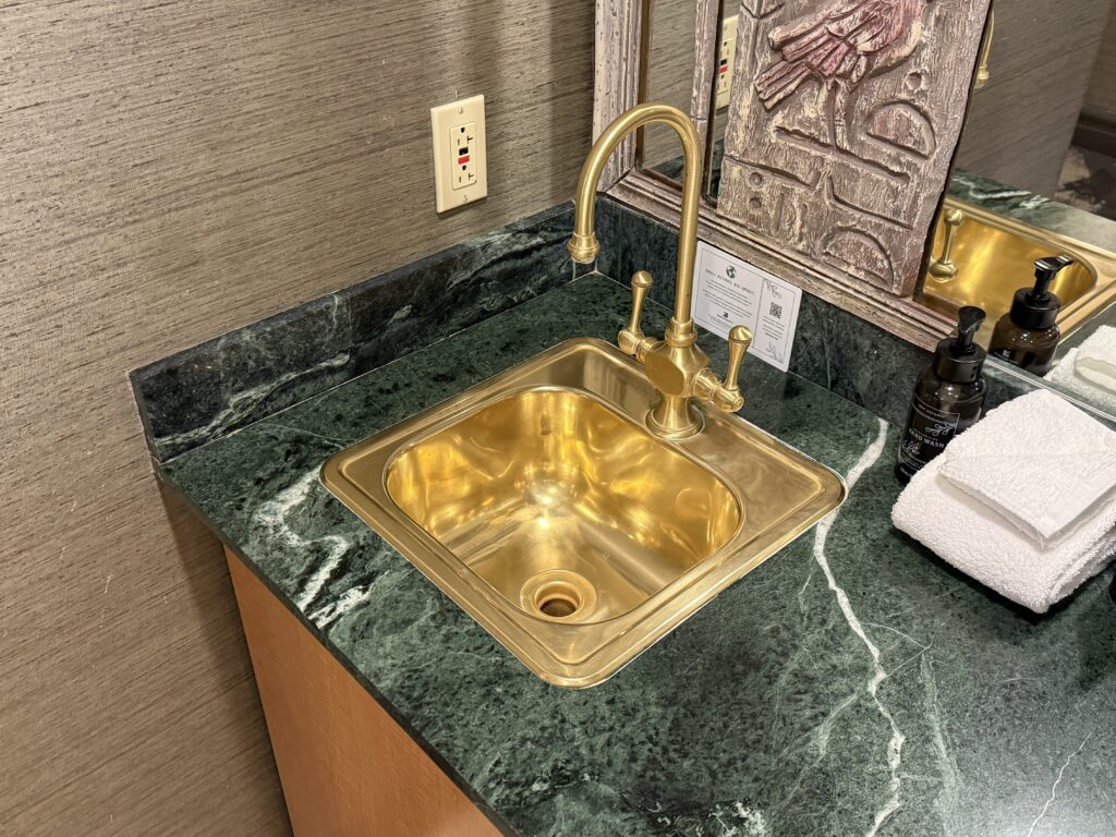 A small brass sink in the green countertop.