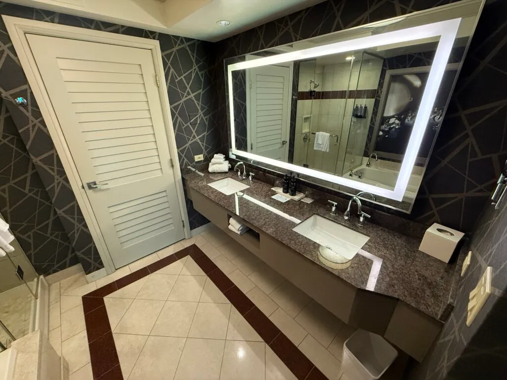 A dual sink vanity with an illuminated mirror above the vanity.