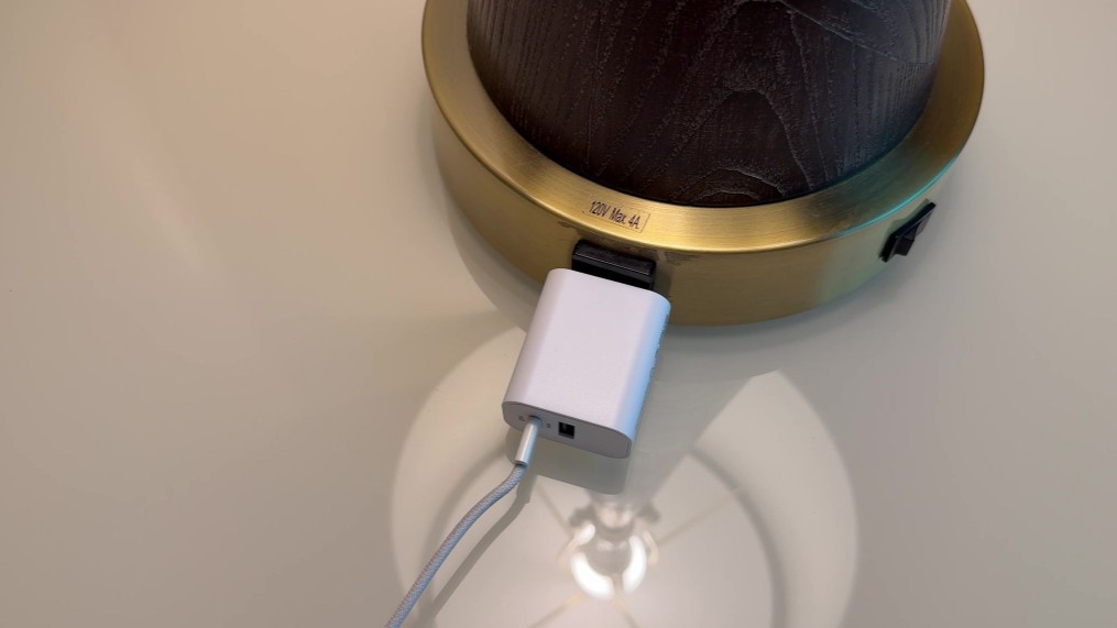 An Iphone charger plugged int othe base of a lamp.