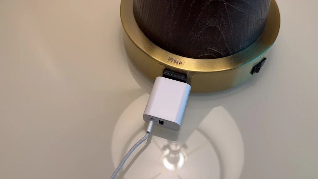 An Iphone charger plugged int othe base of a lamp.
