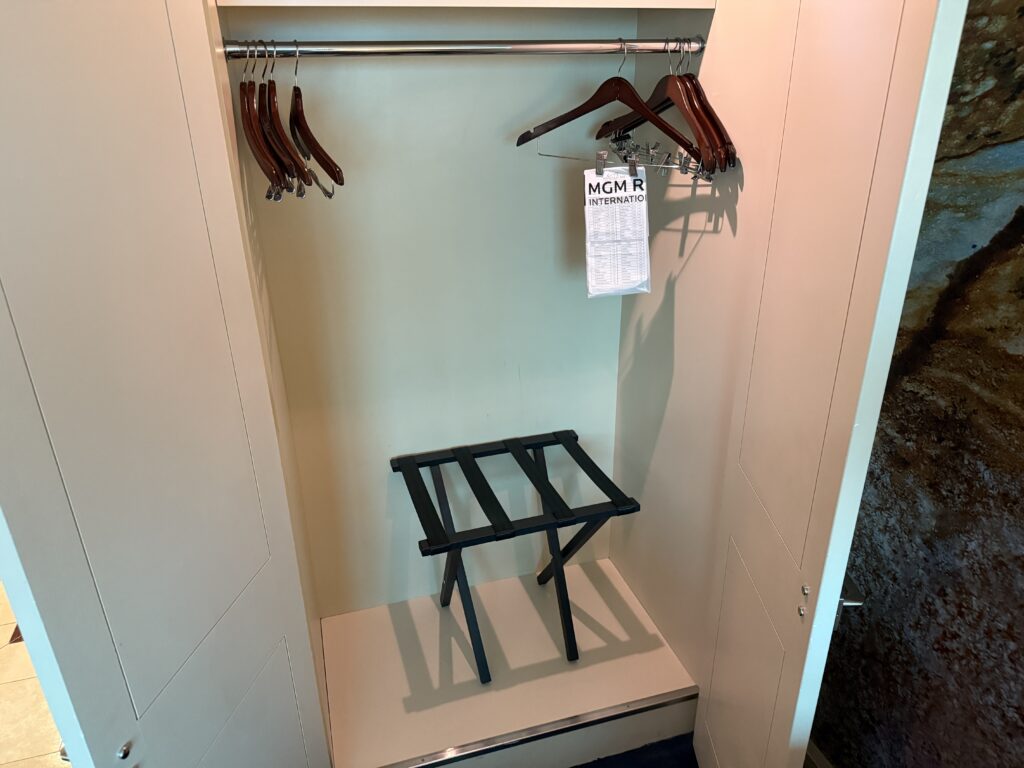 An empty closet with wooden hangers and a luggage stand.