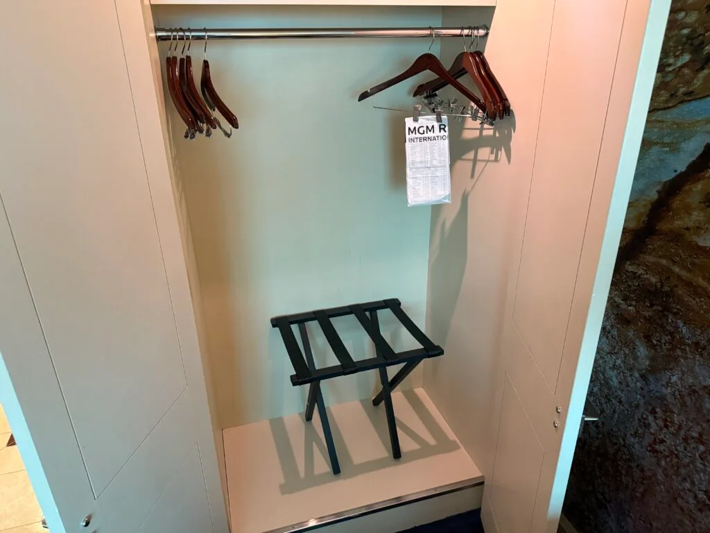 An empty closet with wooden hangers and a luggage stand.