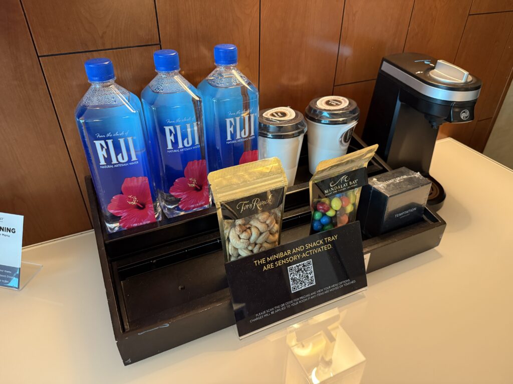 Desktop minibar stocked with waters, dry snacks, and a coffee maker.