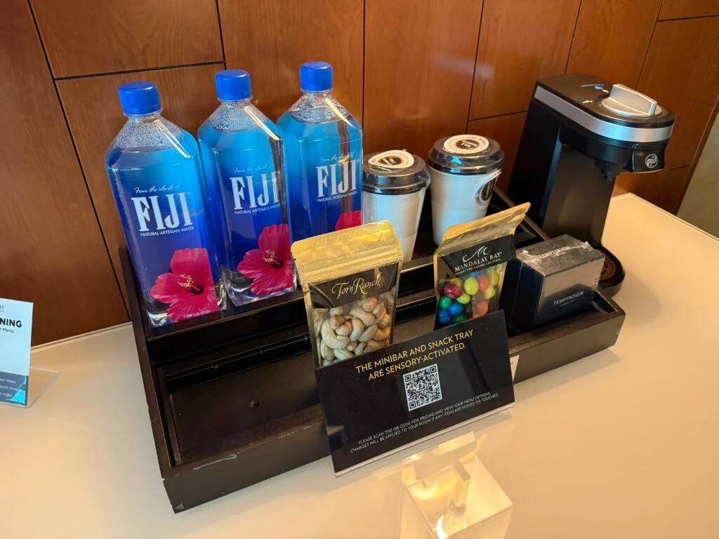 Desktop minibar stocked with waters, dry snacks, and a coffee maker.