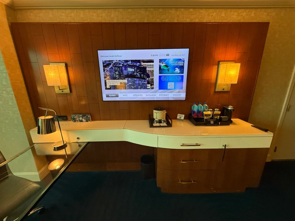 A mounted TV flanked by decroative lights on either side. below, is the mini bar shelf.