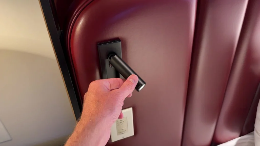 Bedside reading light protruding from the headboard. 