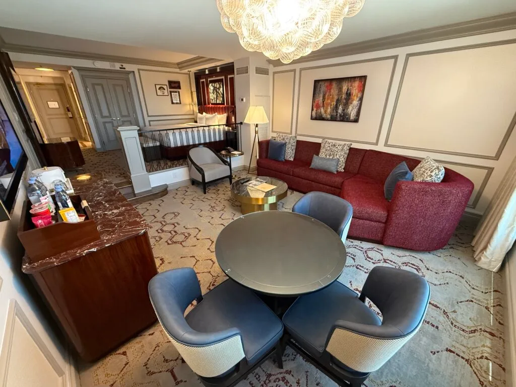 A living area with a small table with 3 chairs, a red couch, and a TV. 