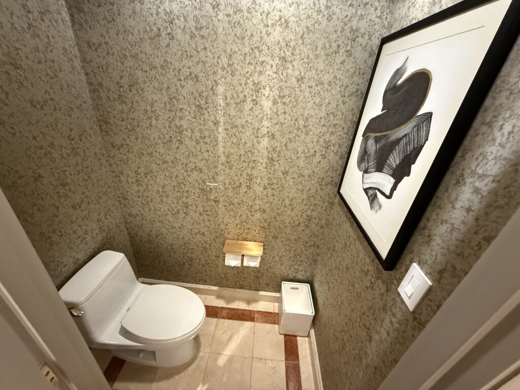 a small room with a toilet facing a wall that has a picture mounted.