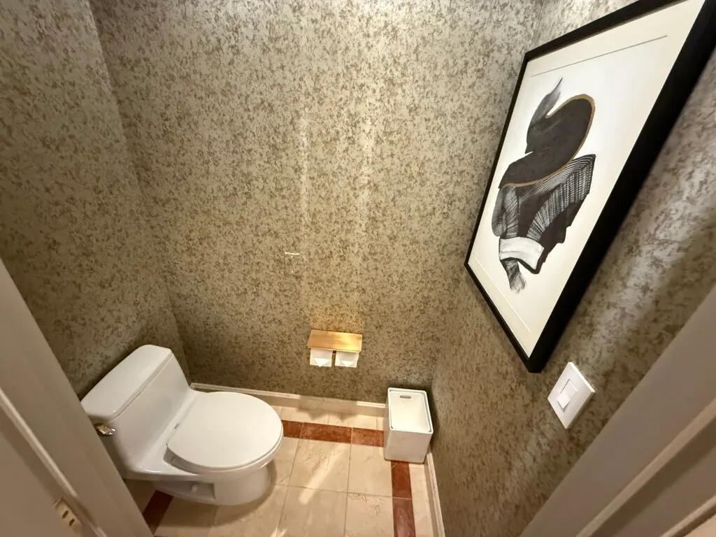 a small room with a toilet facing a wall that has a picture mounted. 