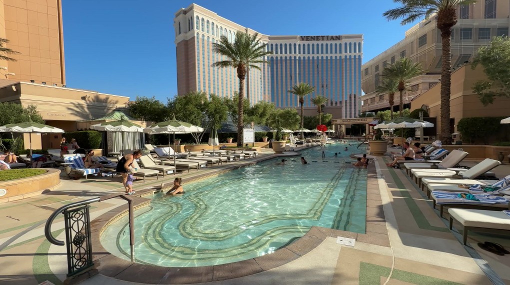 A long skinny pool with Venetian's hotel tower in the background.