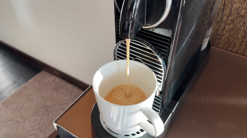 A coffee brewer dispensing coffee into a white mug.