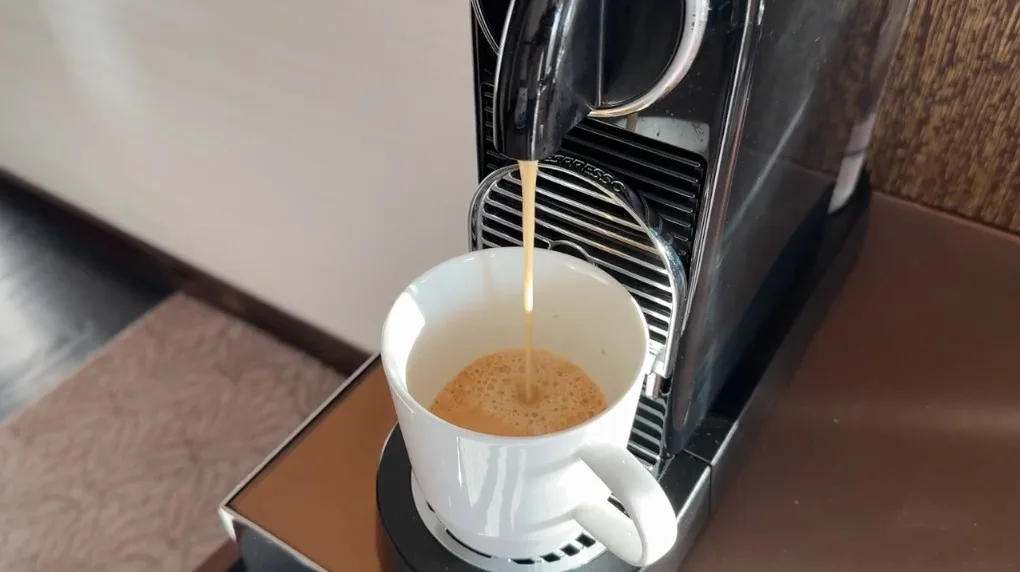 A coffee brewer dispensing coffee into a white mug. 
