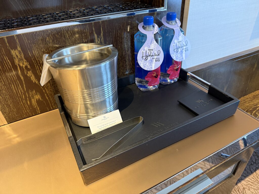 Two fiji water balltles on a tray next to a metal ice bucket.