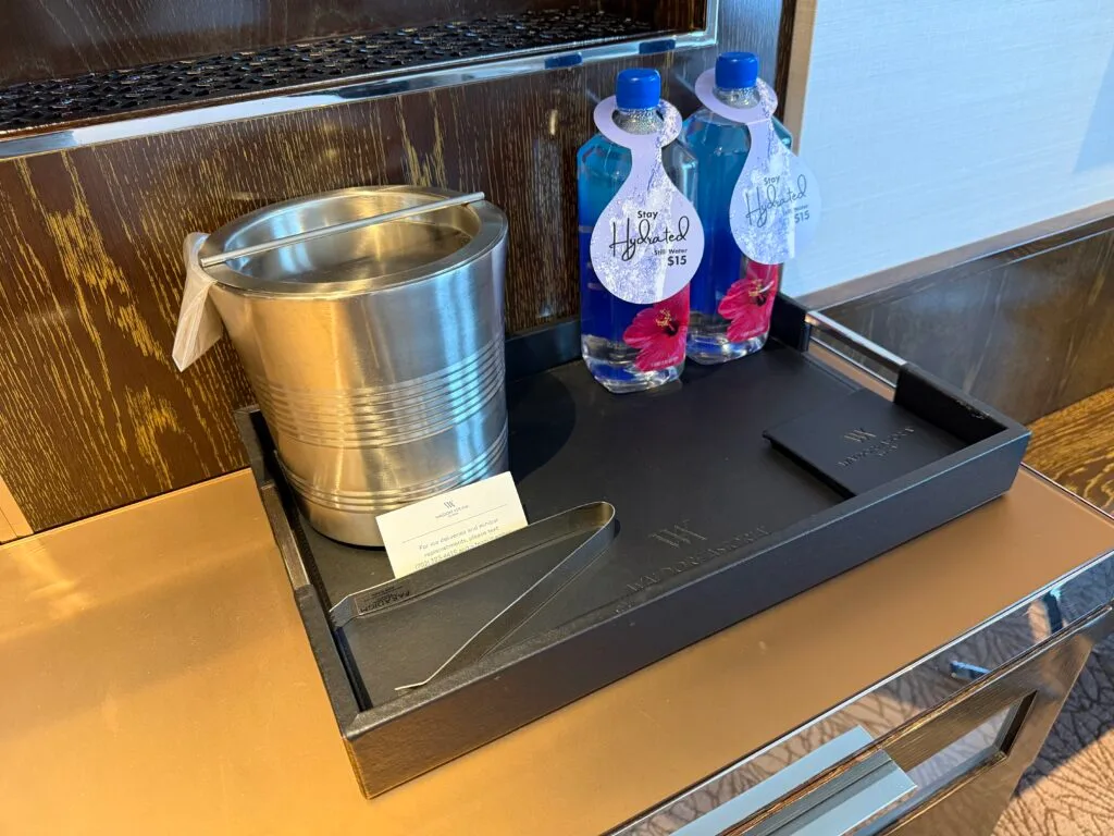 Two fiji water balltles on a tray next to a metal ice bucket. 