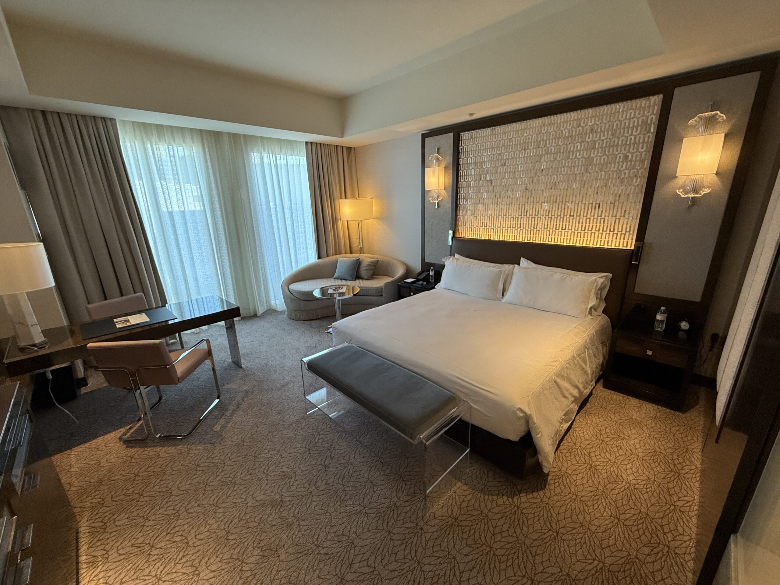 Angle of the room that shows the king bbed with the windows behind it in the backgound.