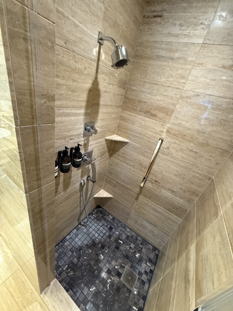 The shower, whichc has complimentary bath products mounted on the wall.