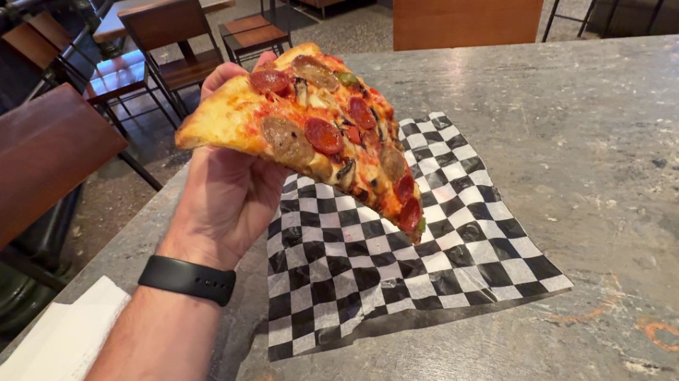 A slice of pizza being held in a hand.