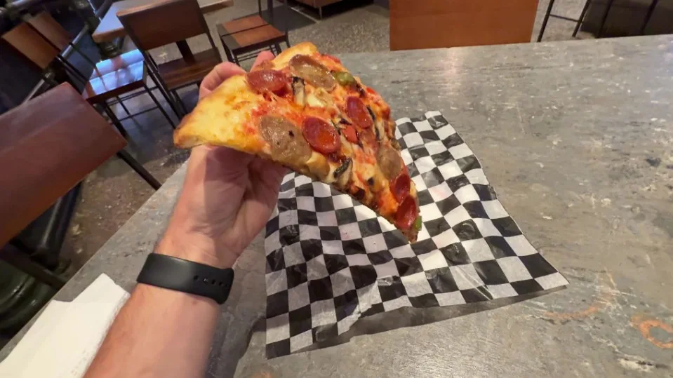 A slice of pizza being held in a hand. 