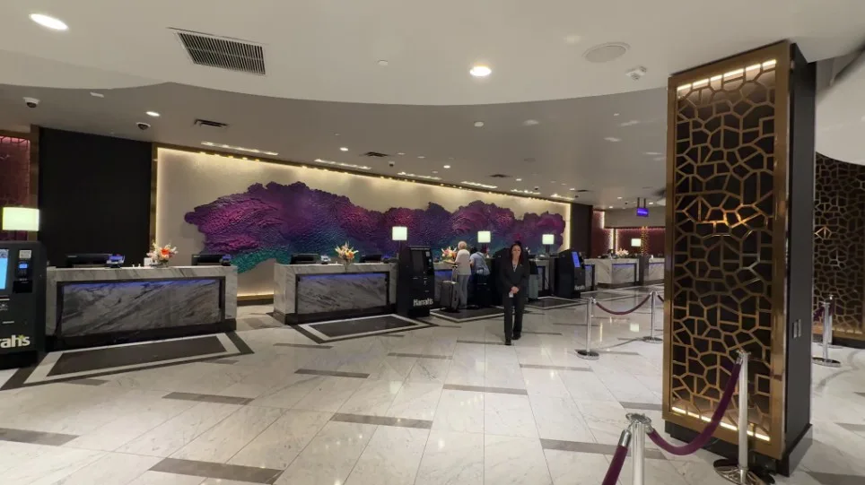 The hotel front desk at Harrah's, which has a decorative accent wall behind it depicting a purple cloud. 