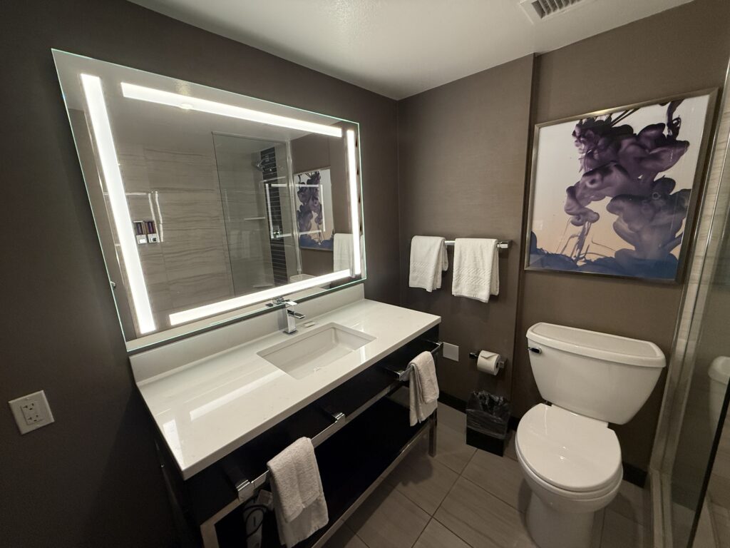 A single sink vanity with an illuminated mirror and toilet to the right.