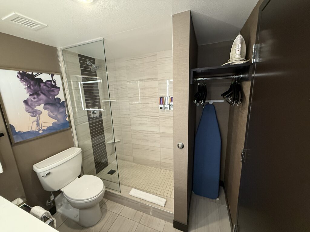 A shower next to the toilet with a half glass partition.