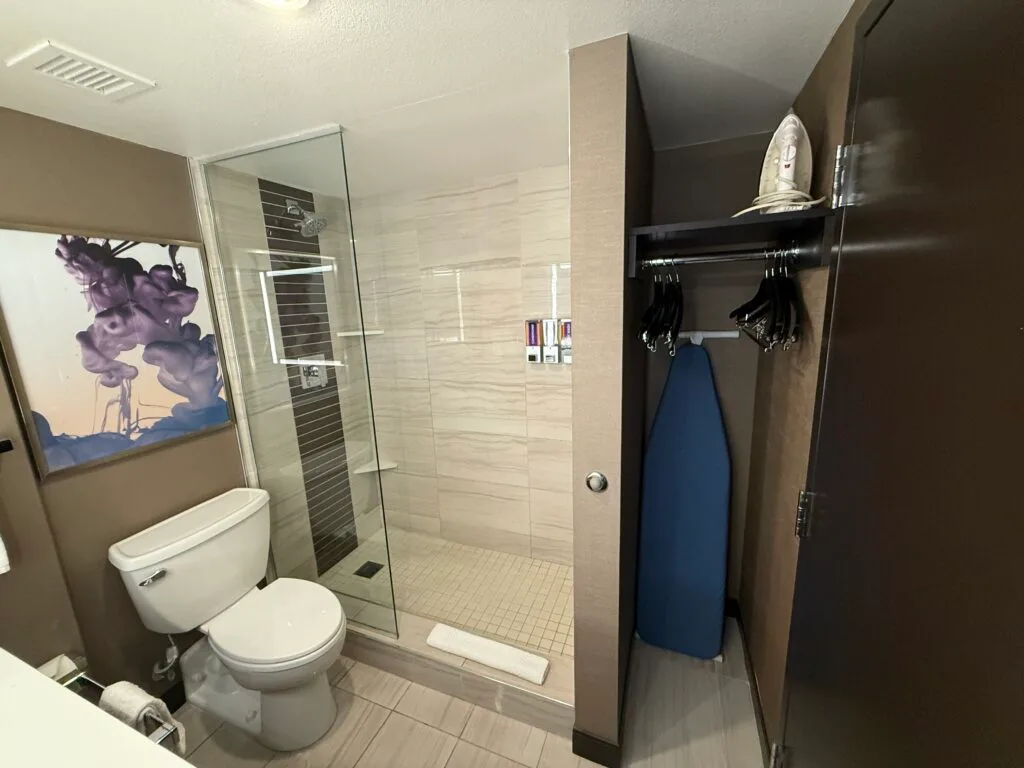 A shower next to the toilet with a half glass partition. 
