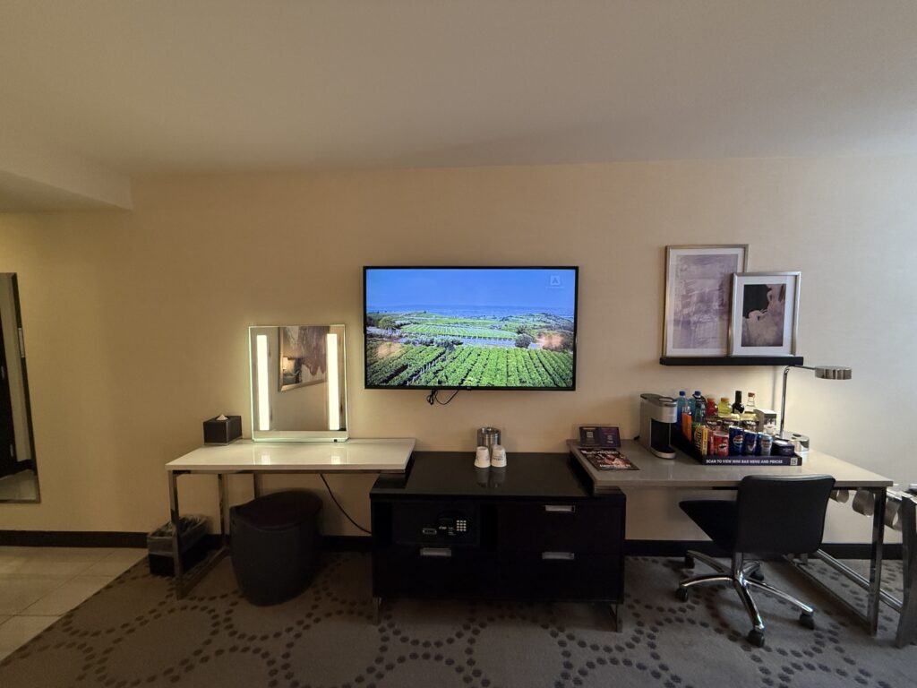 A shot of the TV and the TV stand, mini bar, and work desk below.