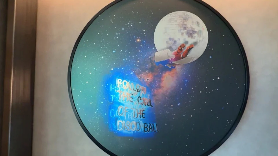 A circular picture with a hand in front of a disco ball in outer space and a quote that says "Follow the call of the disco ball". 