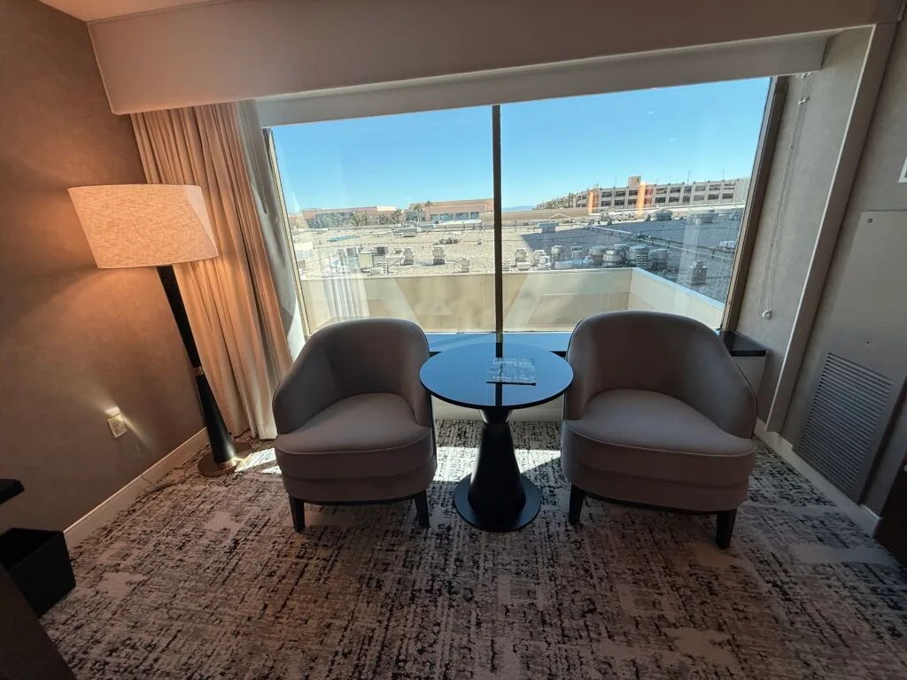 2 chairs and a lamp in front of the window, with a view of MGM Grand's rooftop. 